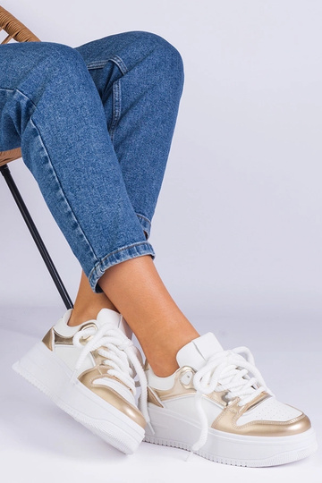 Wit-gouden sneakers op een...