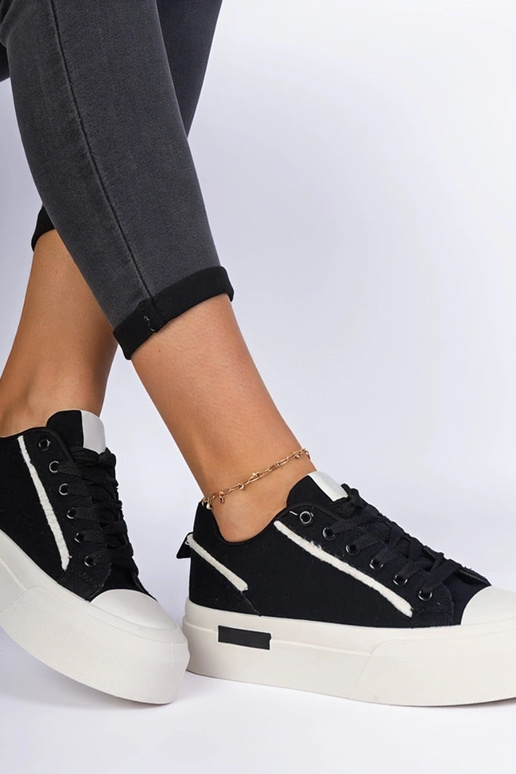 Zwarte damessneakers van stof op een... Zwarte damessneakers van stof op een...