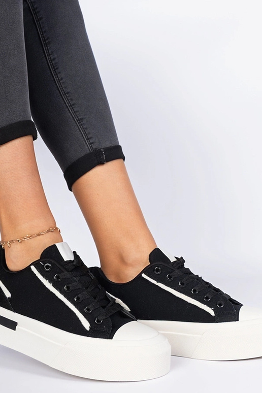 Zwarte damessneakers van stof op een... Zwarte damessneakers van stof op een...