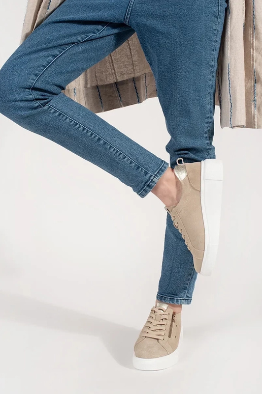 Zandkleurige sneakers model op een... Zandkleurige sneakers model op een...