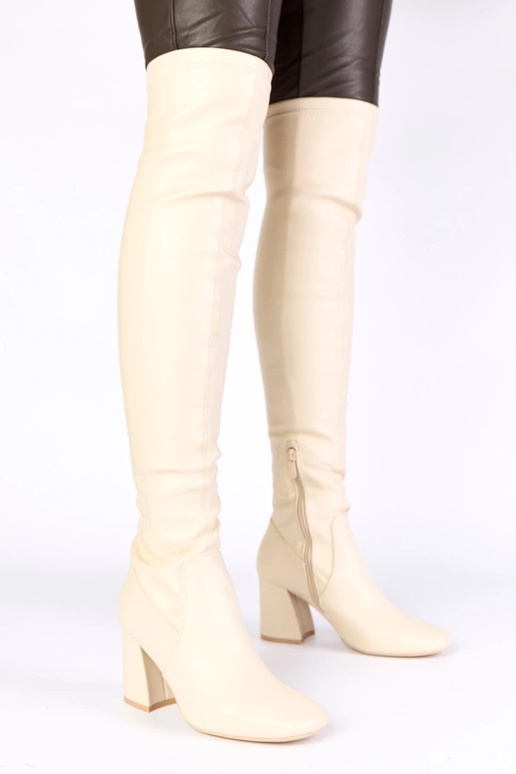 Zandkleurige lange laarzen boven de...