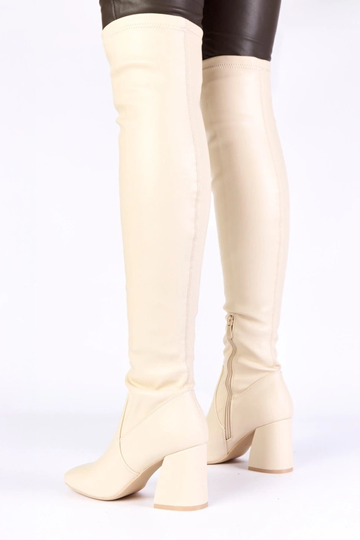 Zandkleurige lange laarzen boven de...