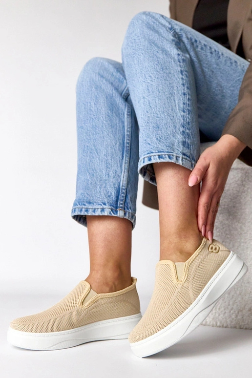 Zandkleurige stoffen sneakers op een...