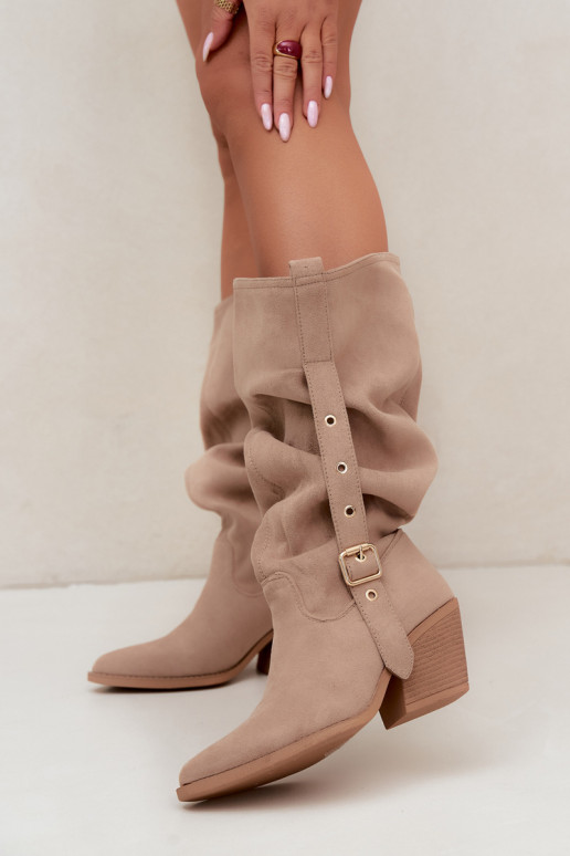 gekruiste dames lange laarzen in cowboystijl met riemen en hakken in zand Adria