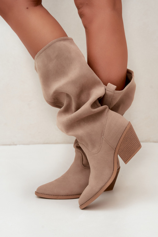 gekruiste dames lange laarzen in cowboystijl met riemen en hakken in zand Adria