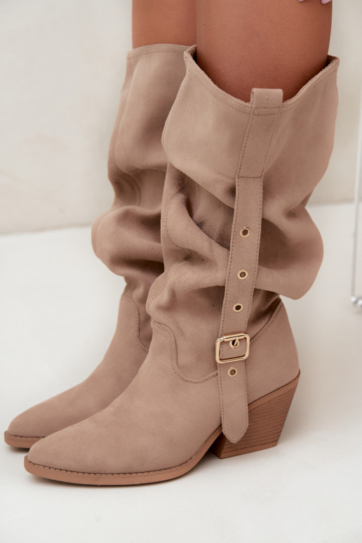 gekruiste dames lange laarzen in cowboystijl met riemen en hakken in zand Adria